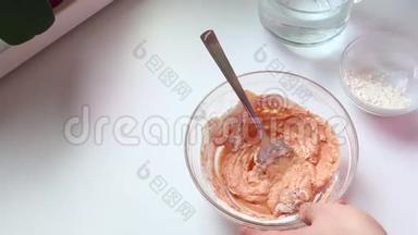 一个男人正在做古拉什酱。 用勺子将番茄酱、酸奶油和面粉放入玻璃容器中搅拌。 加水，再混合..